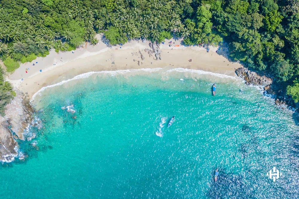 Aerial view of sandy beach with tourists swimming in beautiful clear sea water