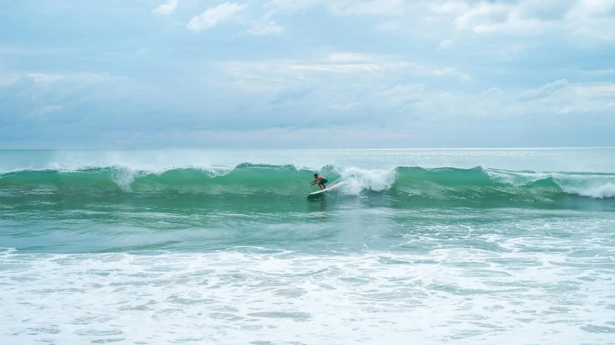 A surfer riding a wave at Kata