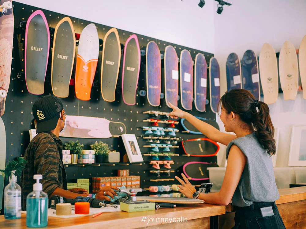 A woman pointing to a skate boards on a wall in Lai Lang Surf & Skate shop