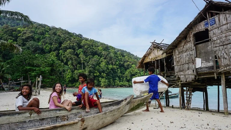 Some sea gypsy kids playing in a wooden boat on the beach