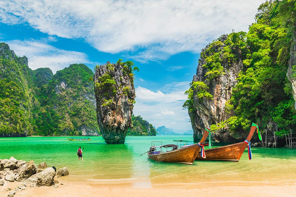 A couple of longtail boats anchored off a beach at James Bond Island