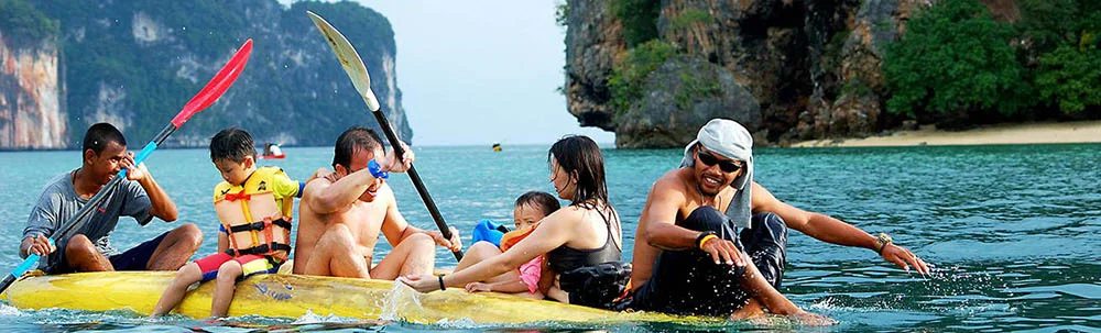 A family being paddled in a sea kayak by their guide